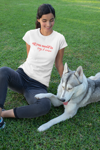 A girl wearing a white shirt that reads ' all you need is dogs & wine'